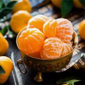Peeled clementines or mandarin oranges in a brass bowl.