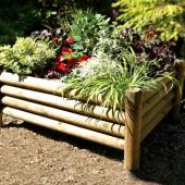 Raised garden bed made from round posts fastened together.